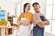 © Krakenimages.com - Two hispanic paint students smiling happy standing with arms crossed gesture at art studio.