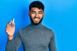 © Krakenimages.com - Arab man with beard holding spark plug looking positive and happy standing and smiling with a confident smile showing teeth