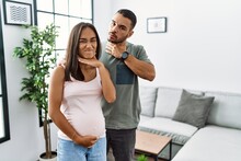 Young Interracial Couple Expecting A Baby, Touching Pregnant Belly Cutting Throat With Hand As Knife, Threaten Aggression With Furious Violence