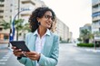 © Krakenimages.com - Young hispanic business woman wearing professional look smiling confident at the city using touchpad device