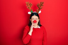 Young Hispanic Woman Wearing Deer Christmas Hat And Red Nose Touching Mouth With Hand With Painful Expression Because Of Toothache Or Dental Illness On Teeth. Dentist