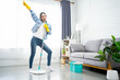 Asian woman having fun while doing housework. She enjoyed singing while mopping the floor in the living room.