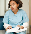 Tired female medical student sitting with study book, portrait. Black intern doctor in uniform exhausted from overworked in a hospital during academic qualification. Professional healthcare occupation