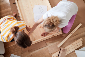 Wall Mural - Mother and daughter assembling new furniture - moving in into a new home.