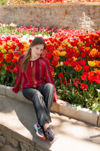 Young Woman Tourist In Red Blouse Sitting In Blooming Tulip Field. Spring Time, Red And Yellow Tulip