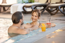 Happy Couple Drinking Juice In The Indoor Swimming Pool