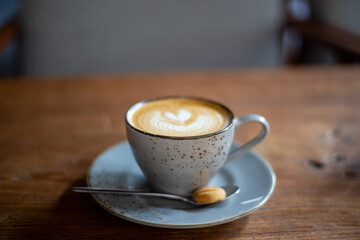 Hot cappuccino coffee cup with heart shape latte art on brown old wooden table at cafe.