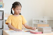 © StockerThings - Asian schoolgirl reading book in her room. A kid enjoy reading books alone. Black hair Thai-Chinese girl concentrate reading book by her own.