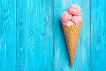 Strawberry Ice Cream In A Waffle Cone On A Blue Background. Top View, Vertical Background.