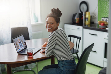 Wall Mural - pretty happy mixed-race woman having video chat with senior female tutor indoors