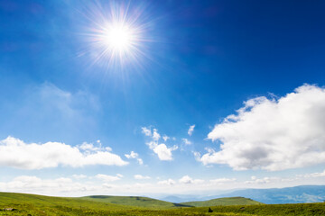 Wall Mural - sun shine on the blue sky. white fluffy clouds above the hilly mountain landscape. beautiful nature background on a sunny summer day at high noon