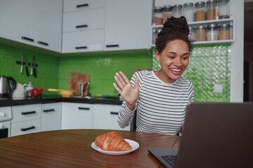Wall Mural - smiling happy female waving hand looking at computer screen during video chat indoor