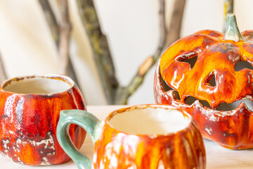 Handmade ceramic pumpkin and cups. Halloween concept. Selective focus.