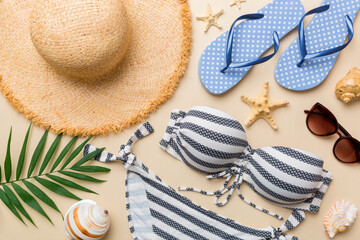 Woman swimwear and beach accessories flat lay top view on colored background Summer travel concept. bikini swimsuit, straw hat and seasheels. Copy space Top view