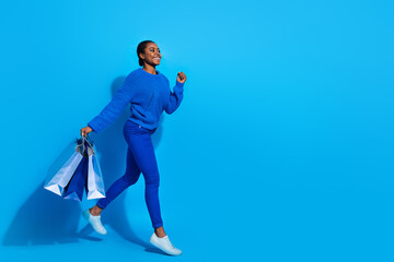 Wall Mural - Full length body size view of attractive cheerful girl jumping running carrying bags copy space isolated over bright blue color background