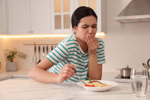 Young Woman Feeling Nausea While Eating At Table In Kitchen
