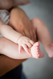 Fototapeta  - Rodzice trzymają w rękach swoje malutkie dziecko, stopy i rączki dziecka w dłoniach rodziców