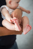 Fototapeta  - Rodzice trzymają w rękach swoje malutkie dziecko, stopy i rączki dziecka w dłoniach rodziców