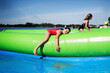 Dzieci bawią się na zjeżdżalni wodnej na świeżym powietrzu, Dziewczynka odpoczywa po zabawie w wodzie nad jeziorem w pełnym słońcu