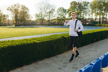  Sport and health concept - young guy posing at stadium, soccer field with green grass.