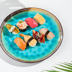 Canvas Print - Nigiri sushi set on ceramic plate in minimal style. Nigiri sushi assorted with fish, crab, eel, tuna, shrimp, salmon and avocado. Simple sushi set on white background with hard shadows.