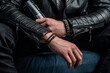 Men's bracelets on the hands. Business attire, leather jacket and magazine