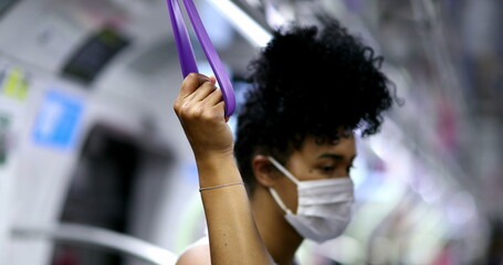 Wall Mural - African american woman holding subway handrail during pandemic wearing face mask