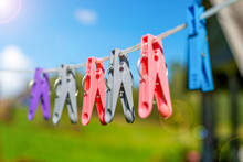 Colorful Clothespins Hang On The Clothesline,  Taken In Backlit And Sun Glare.    The Concept Of Washing Clothes And Linen In Nature.