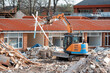 Demolition of an old building with an excavator to give way for a new housing site and piles of rubble