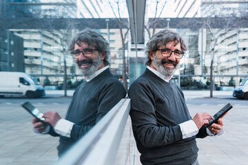 Portrait of contemporary senior man using digital tablet and browsing internet while standing against window, copy space