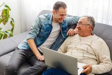 Adult Son Helping Senior Father With Computer At Home