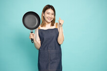 Young Asian Woman Housewife Wearing Kitchen Apron Cooking And Holding Pan Isolated On Green Background
