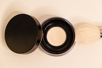 Presentation of the brand and packaging. Professional face powder with a light brush on a white background. Foundation for the face. Cosmetic products. Close-up. Top view. Place to copy.