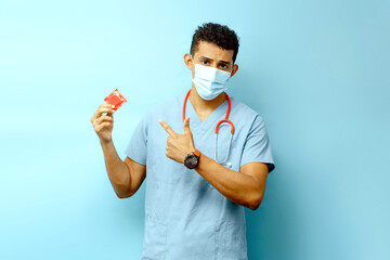 Wall Mural - medical male holding and pointing a condom, protection and illness, aids concept.