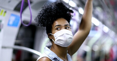 Wall Mural - Young black woman commuting in subway holding handrail wearing face mask