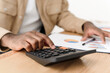 © etonastenka - Close up is the hand of a black man doing calculations on a calculator at home. Maintaining a household budget, calculating mortgage payments