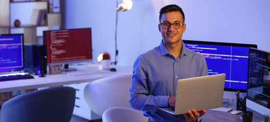 Portrait of handsome programmer with laptop in office