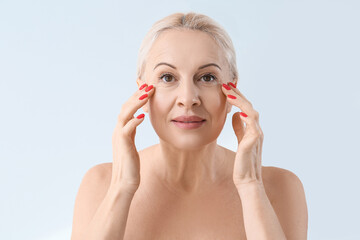 Poster - Mature blonde woman with healthy skin on light background, closeup