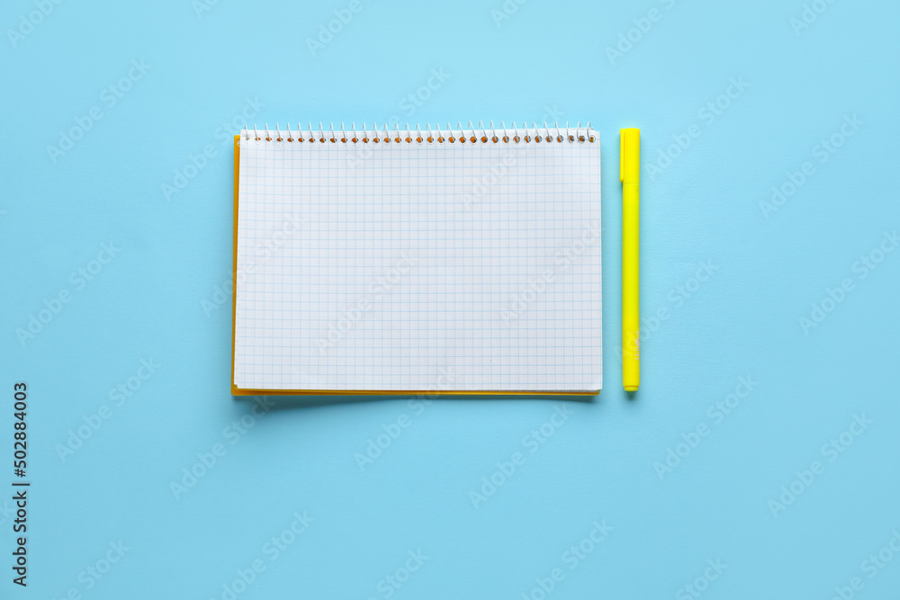 Notebook and pen on light blue background