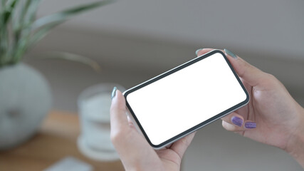 Wall Mural - Close up view woman holding smart phone in horizontal position. Empty screen for advertising text.