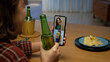 © ChayTee - Young happy attractive asia female enjoy relax night party event online celebration festive with friends at home sofa pr table clinking beer with glass and bottle drinking via online videocall.
