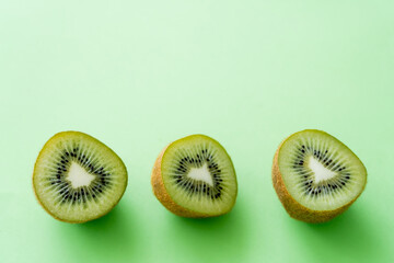 Wall Mural - top view of kiwi fruit halves on green.