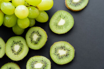 Wall Mural - top view of green grapes and sliced kiwi on black.