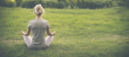 Wall Mural - Woman sitting in active wear in lotus position in nature.