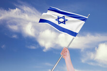 Female Hand Is Waving Israeli Flag Against Blue Sky With Clouds