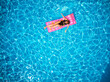 © artiemedvedev - Fit pretty girl in bikini chilling on inflatable pink mattress in swimming pool. Slim hot woman in swimwear tanning. Female relaxing on float in blue water at luxury resort. Aerial, view from above.