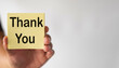© Pakorn - Selective Focus Hand holding yellow sticky note with Thank You word over white background with copyspace.
