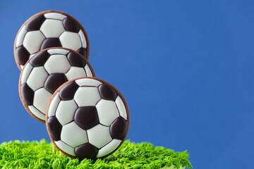 Birthday cake for a football fan with green cream cheese frosting, grass and soccer balls gingerbread cookies on top.