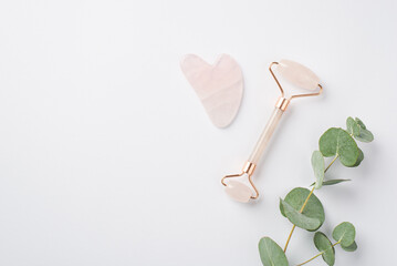 Wall Mural - Top view photo of eucalyptus rose quartz roller and gua sha on isolated white background with copyspace