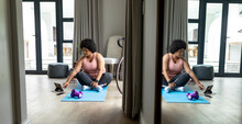 African American Mid Adult Woman Using Digital Tablet While Exercising At Home
